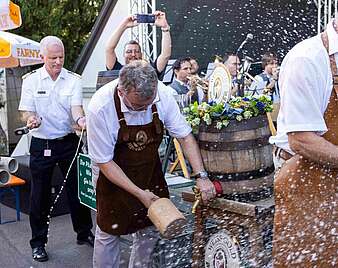 Männer stechen Bierfässer an