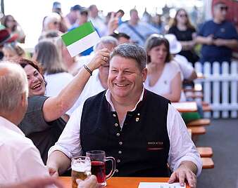 Menschen sitzen an Biertischen